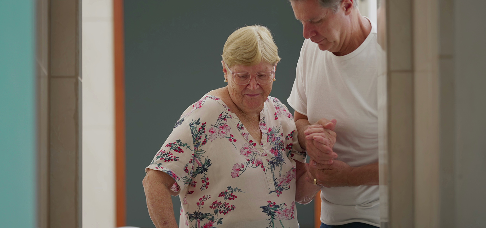 Cuidador ayudando a una mujer a caminar Cuidador ayudando a una mujer a caminar